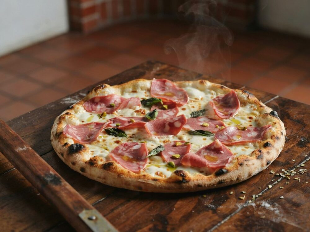 pizza z mortadelą na drewnianej desce